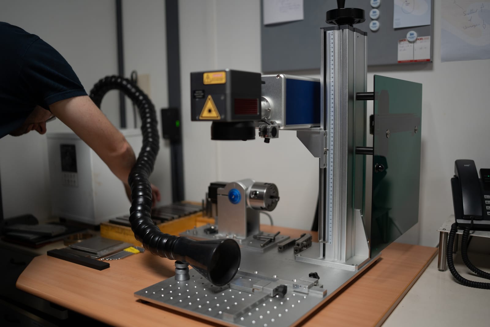 Onze fiberlaser, met een collega die een deel klaarzet voor het graveren