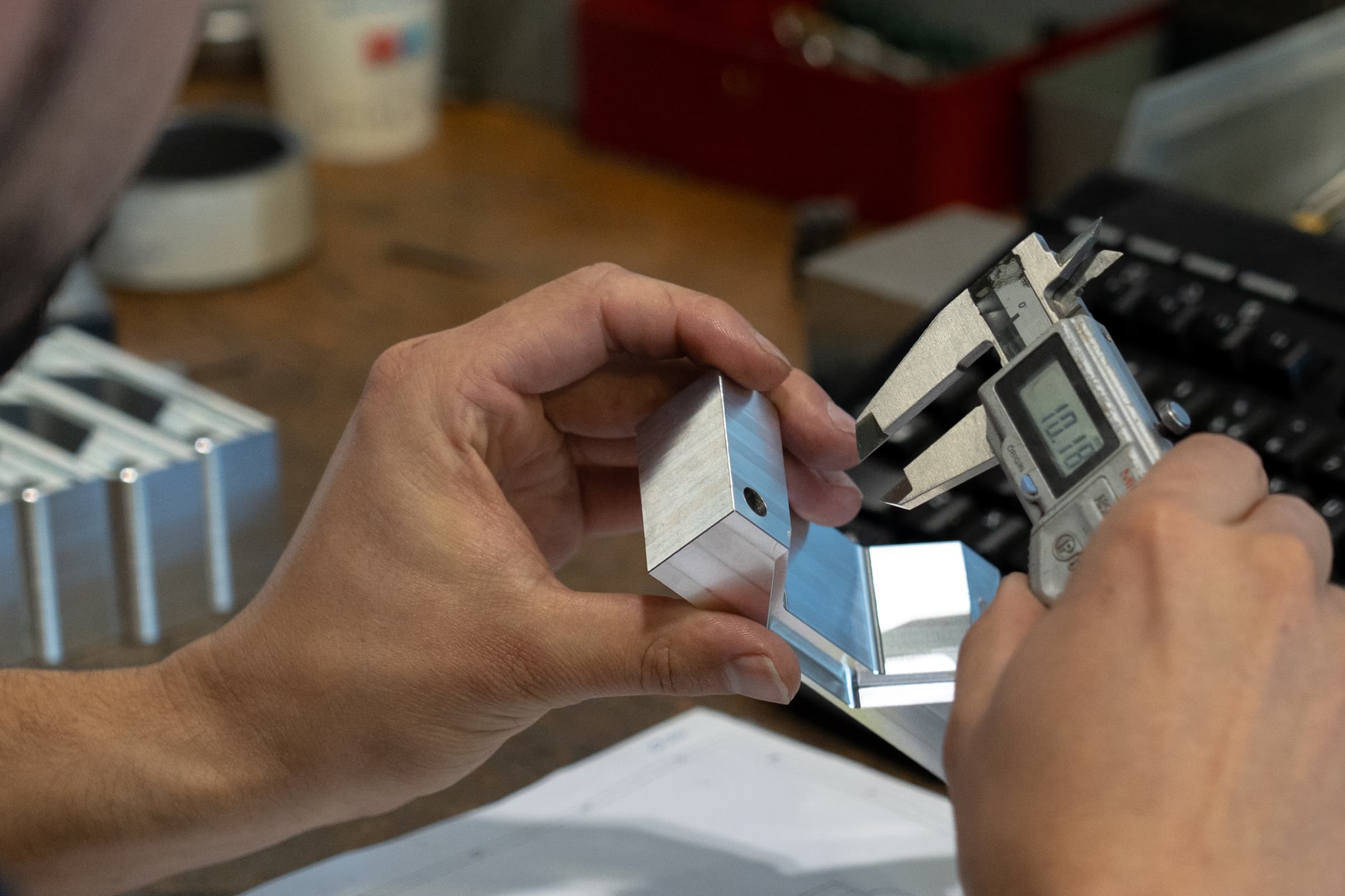 Een gefreesd aluminium deel wordt nagemeten met de schuifmaat